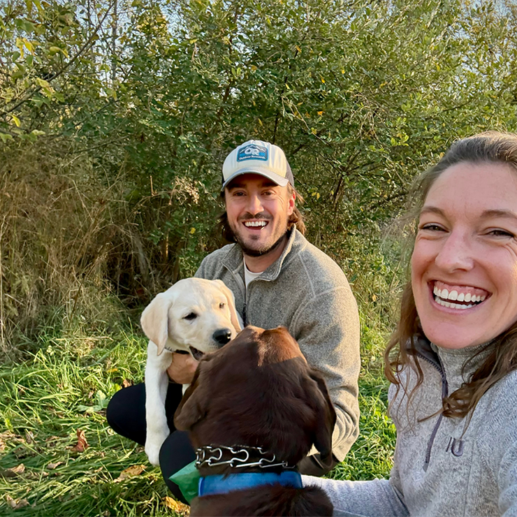 Scientists Ross Jacobucci and Brooke Ammerman and their dogs at a state park surrounded by greenery.
